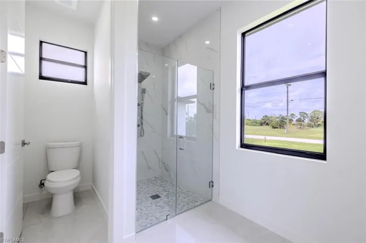 Full bath featuring a marble finish shower and light tile patterned floors