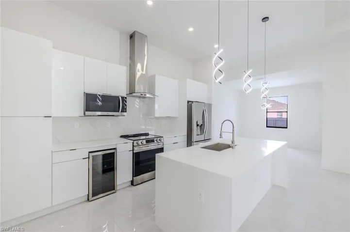 Kitchen featuring decorative backsplash, decorative light fixtures, white cabinetry, modern cabinets, and an island with sink