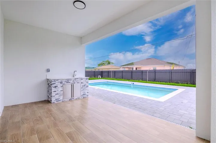 View of swimming pool with a patio area, a fenced backyard, and exterior kitchen