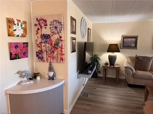 Entrance from kitchen to living room, corner nook and paneled walls, elevated shelf for TV, laminate flooring