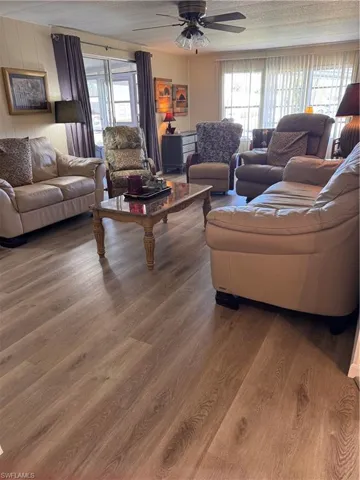 Living room featuring wood-type flooring, a textured ceiling, and ceiling fan