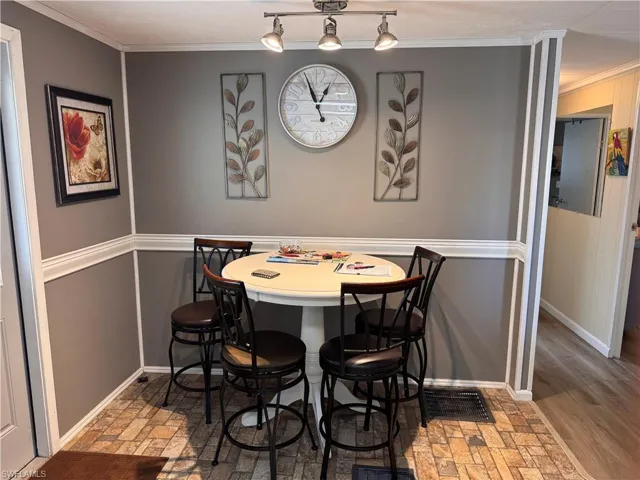 Eat in kitchen dining space with crown molding and vinyl flooring