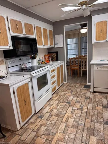 Kitchen featuring backsplash, dishwashing machine, range oven, microwave, and ceiling fan