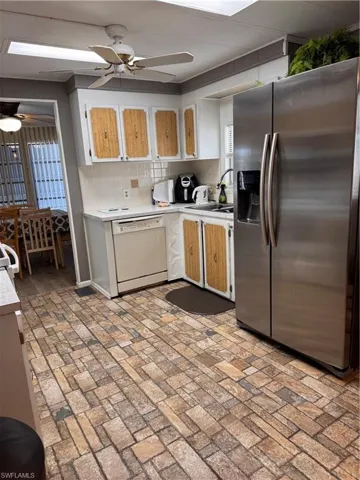 Kitchen with refrigerator, backsplash, dishwashing machine, ceiling fan, and sink