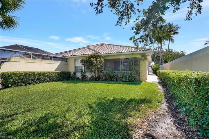 Rear exterior featuring a tiled roof, stucco siding, screened lanai, and a substantial lawn area