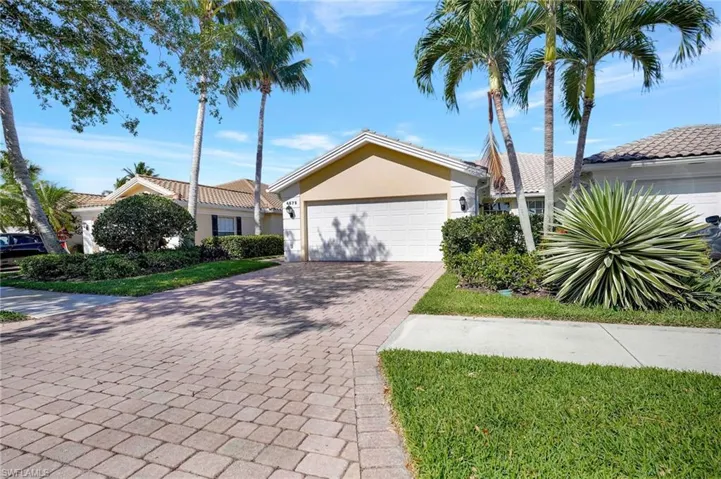 Single-story residence featuring a two-car garage with a paneled door, a paver driveway, and a tile roof