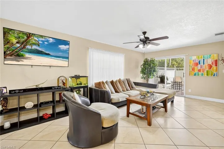 Living area with ceiling fan, light tile patterned floors, and a textured ceiling