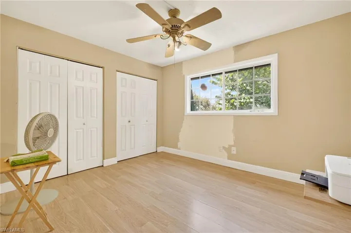 Unfurnished bedroom featuring multiple closets, light wood-type flooring, and ceiling fan