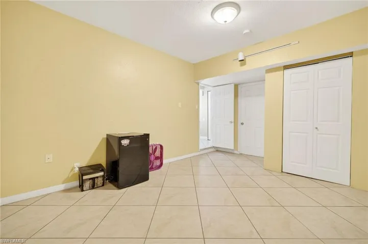 Unfurnished bedroom with light tile patterned floors, a closet, and refrigerator