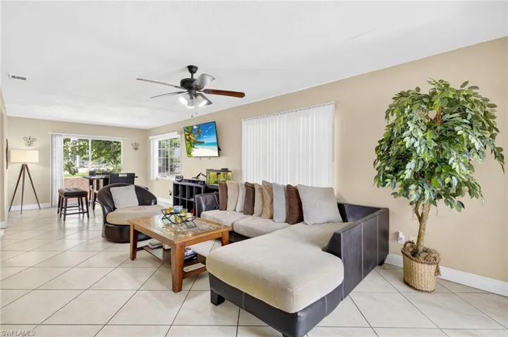 Living area with a ceiling fan and light tile patterned floors