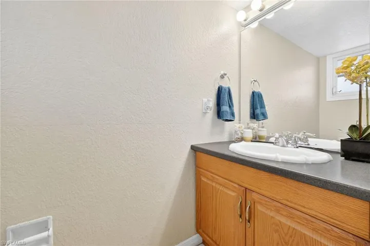 Bathroom with a textured wall, vanity, and a textured ceiling