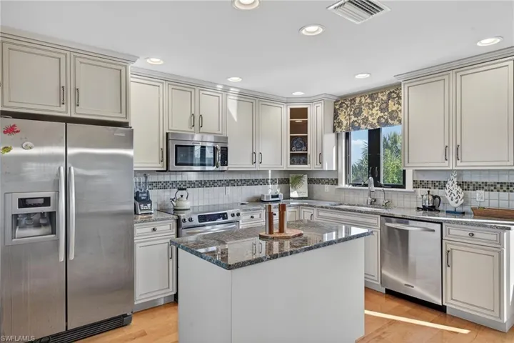 Kitchen featuring appliances with stainless steel finishes, dark stone countertops, light wood-style flooring, recessed lighting, and a kitchen island