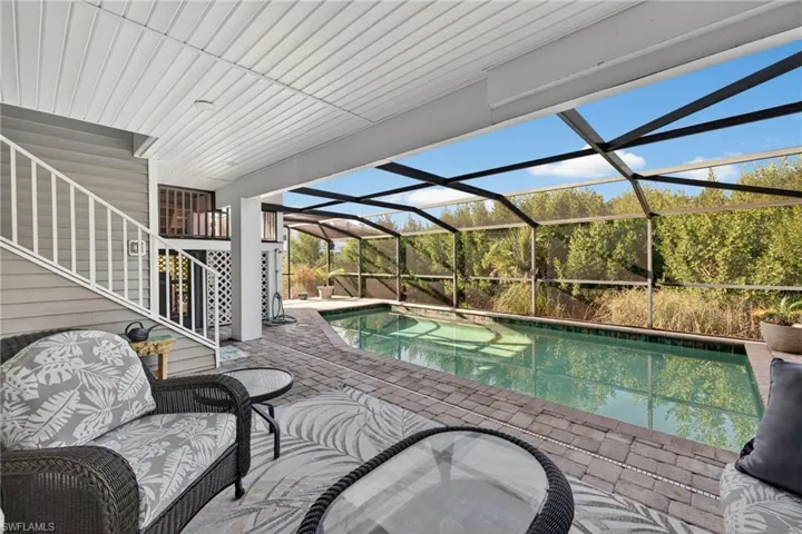 Swimming pool featuring a sunroom, a lanai, a patio, and stairs