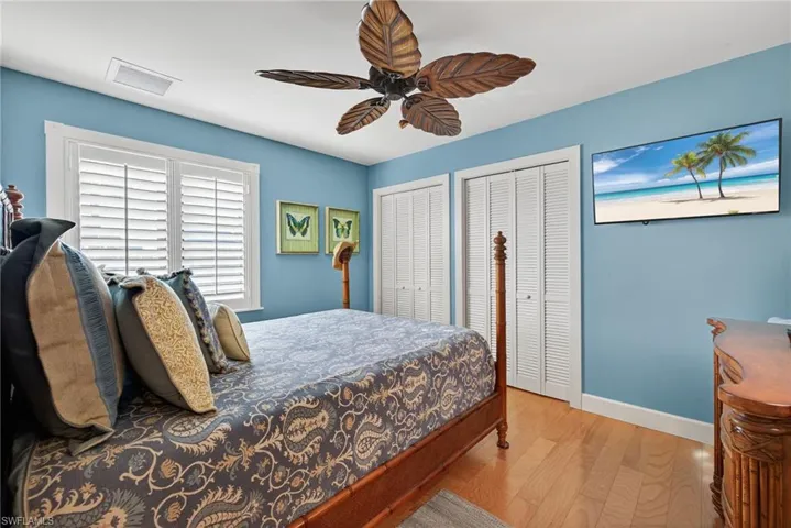 Bedroom with wood finished floors, multiple closets, and ceiling fan