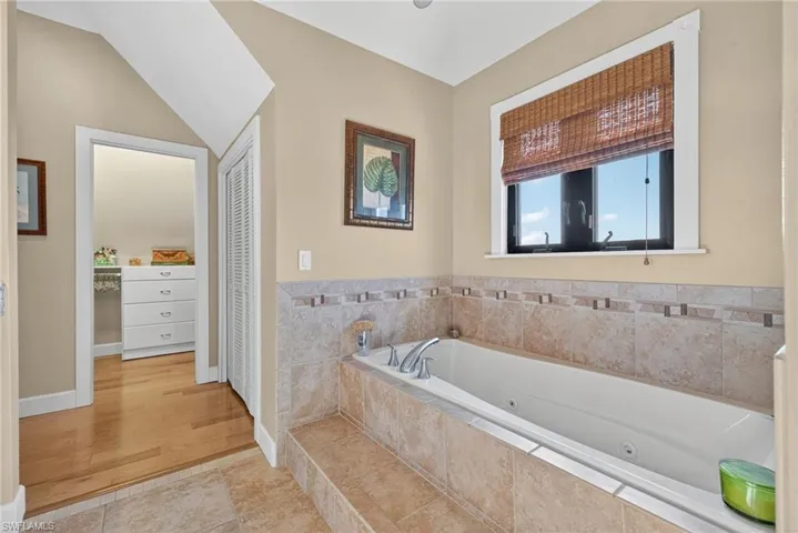 Full bathroom featuring a closet, a whirlpool tub, and light tile patterned floors