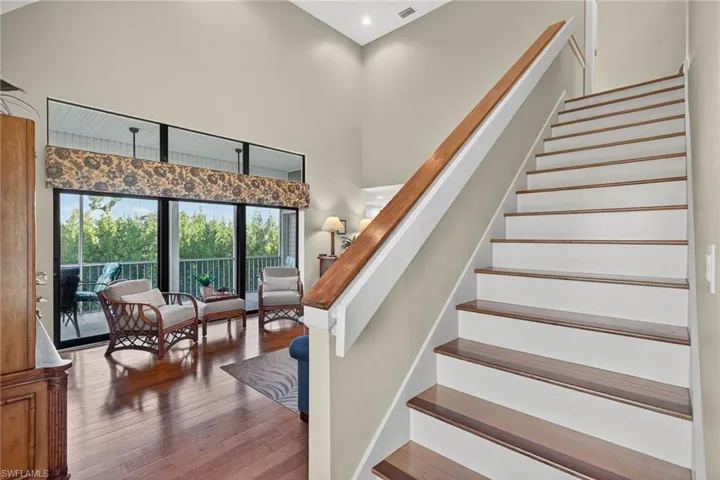 Staircase with hardwood / wood-style flooring and a high ceiling