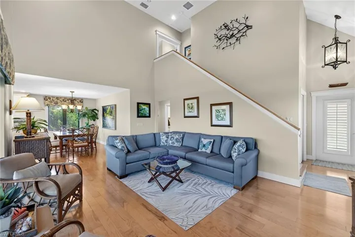 Living room with a chandelier, a high ceiling, light wood-style floors, and stairs