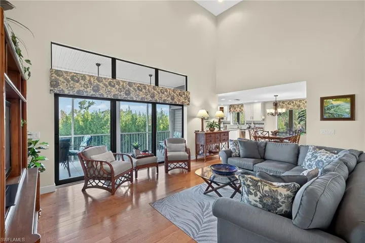 Living room with hardwood / wood-style flooring, plenty of natural light, a chandelier, and a towering ceiling