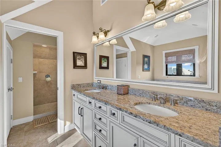 Full bath featuring double vanity, walk in shower, and light tile patterned floors