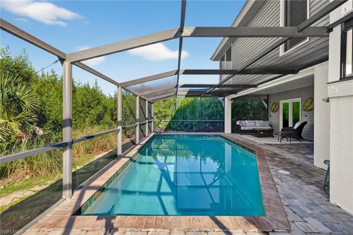 Outdoor pool featuring a sunroom, glass enclosure, a patio, and outdoor lounge area