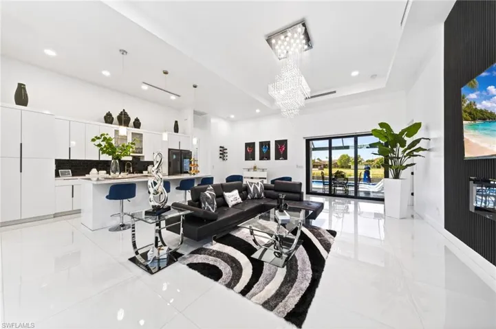 Open-concept living space with sleek white tile flooring and a multi-tiered crystal chandelier