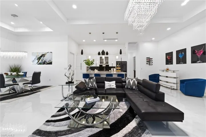 Open-concept living space featuring high ceilings with recessed lighting, bright white flooring, and a modern kitchen with a breakfast bar
