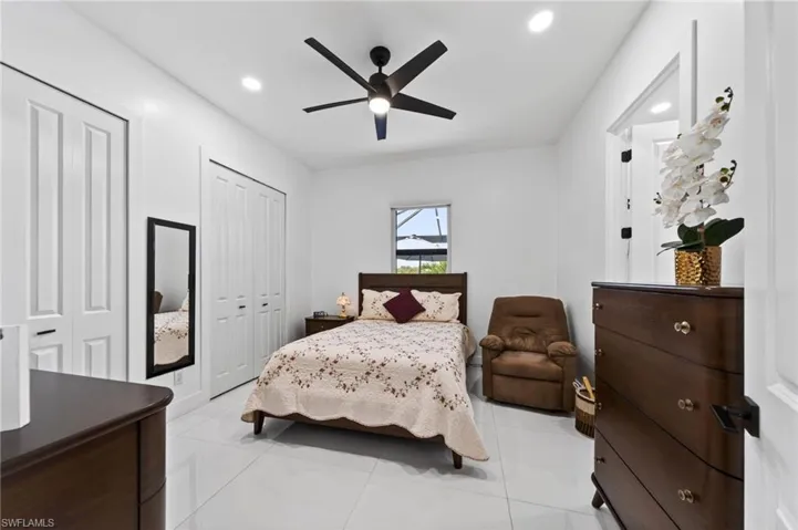 2nd bedroom, Bright interior featuring white walls and tile flooring, a dark wood-finish ceiling fan, recessed lighting, and white bi-fold closet doors and full bathroom