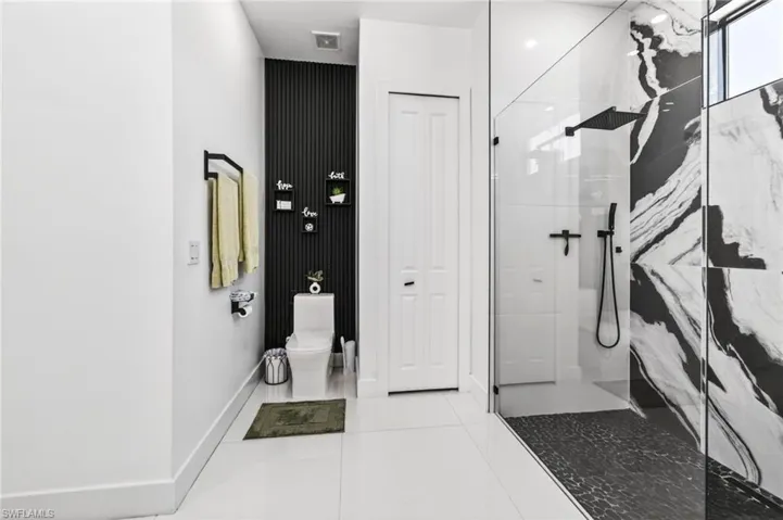 Contemporary bathroom featuring a spacious glass-enclosed shower with black and white patterned wall tile, a rainfall showerhead, and a handheld spray
