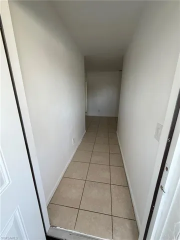 Hallway featuring light tile patterned floors and baseboards