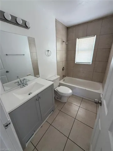 Full bathroom with shower / tub combination, light tile patterned floors, and vanity