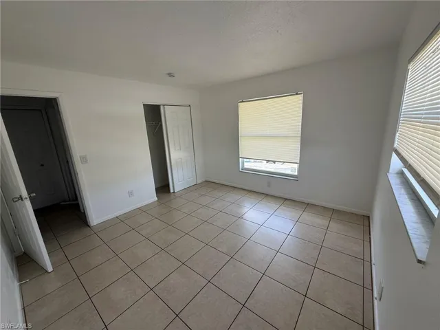 Unfurnished bedroom featuring light tile patterned floors, a closet, multiple windows, and a textured ceiling