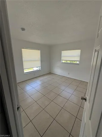 Empty room featuring light tile patterned floors and a textured ceiling
