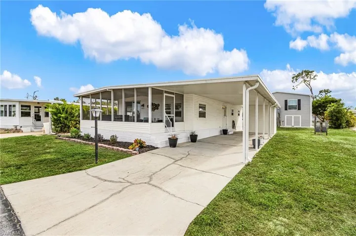 Exterior featuring a screened porch, covered carport, mature landscaping, and a concrete driveway
