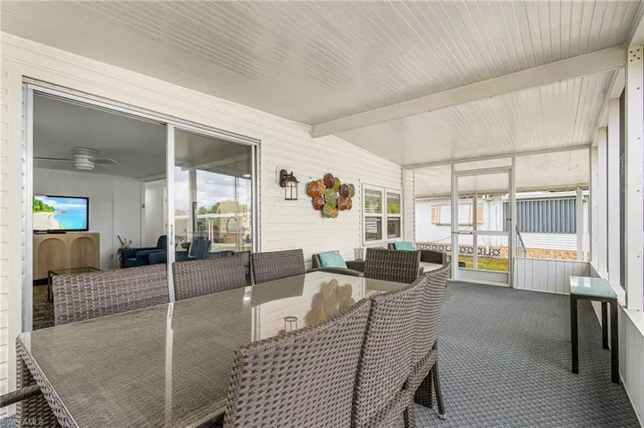Screened porch featuring a textured floor, white paneled walls, and a white ceiling