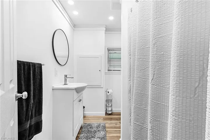 Bathroom featuring a white vanity with integrated sink, chrome faucet, and circular black-framed mirror