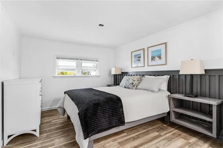 Bedroom featuring wood-finish flooring, white walls, and crown molding