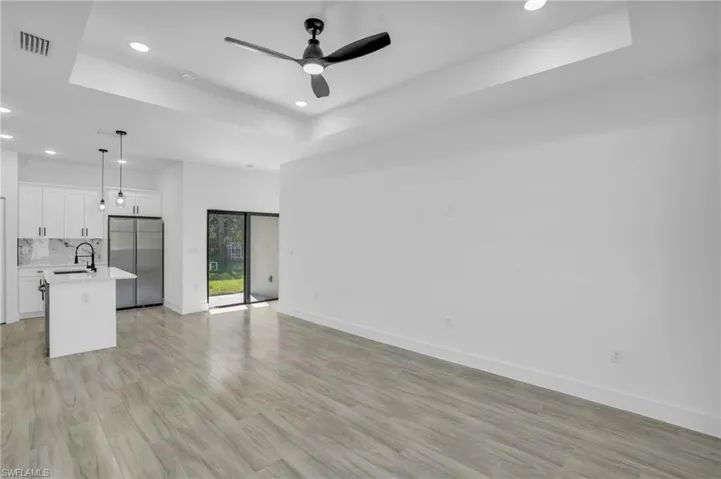 Unfurnished living room with a tray ceiling, light hardwood / wood-style flooring, ceiling fan, and sink