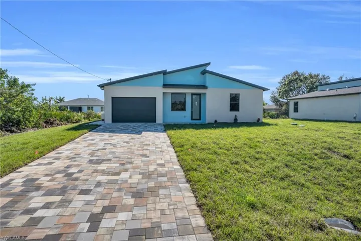 View of front of home with a garage and a front lawn