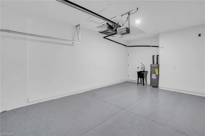Garage featuring electric water heater and a garage door opener