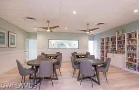 Clubhouse card tables and library for your enjoyment with ceiling fan, a drop ceiling, and light wood-type flooring