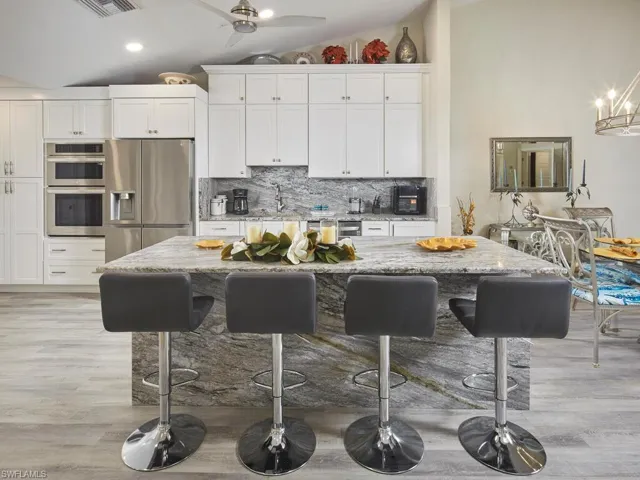 Kitchen featuring white cabinetry, beautiful grey/black/white granite uniquely designed. stainless steel appliances, and a center island