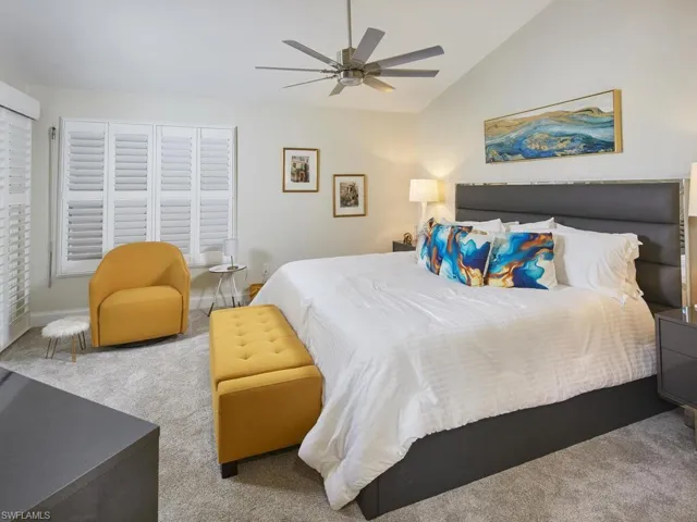Carpeted bedroom with ceiling fan and vaulted ceiling