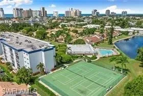 Drone / aerial view with the tennis pickleball courts, clubhouse with pool over-looking lake