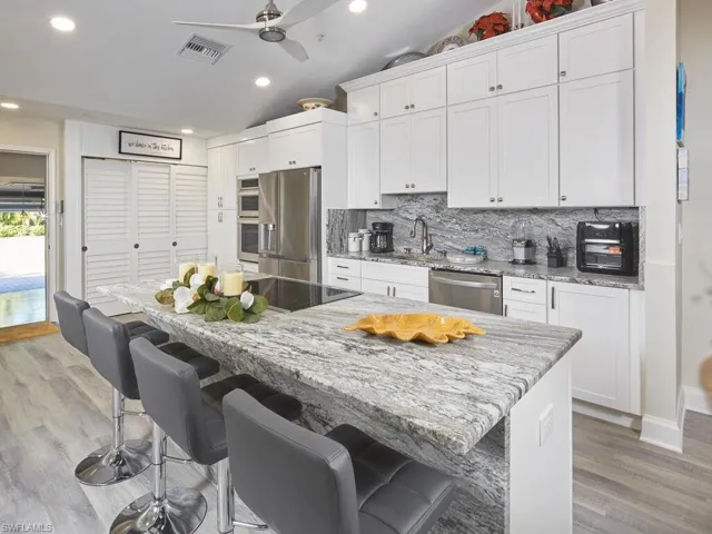 Kitchen with a kitchen island, white cabinetry, and flowing textured granite pattern