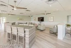 Kitchen with a large island, white cabinets, a kitchen bar, and light hardwood / wood-style flooring