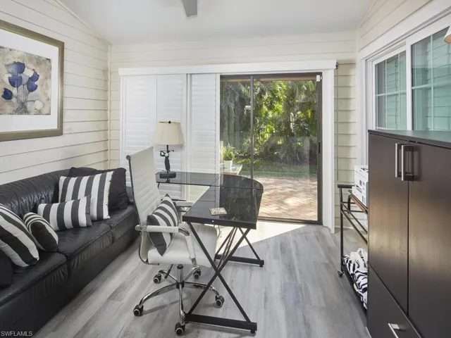 Home office featuring wood vinyl flooring, skylights, lofted ceiling, and wooden walls