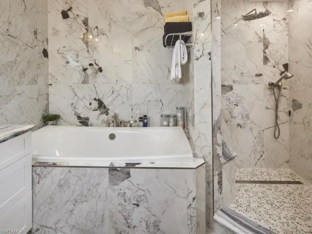Bathroom featuring vanity, separate shower and tub, and tile walls