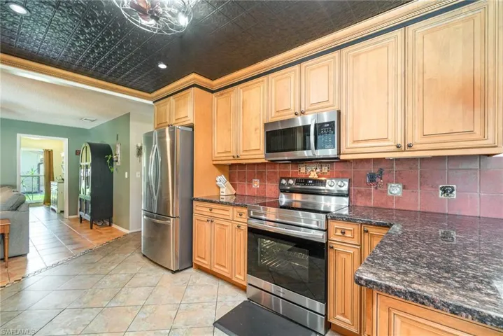 Kitchen featuring backsplash, an ornate ceiling, stainless steel appliances, and baseboards