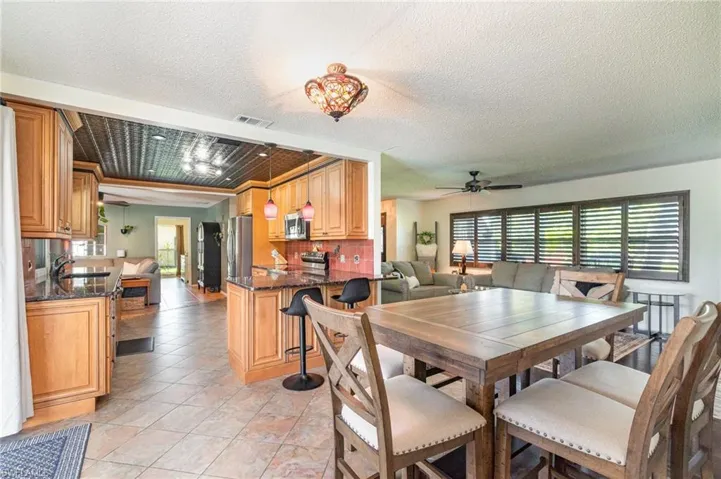Dining space with  light tile patterned floors, visible vents, and ceiling fan