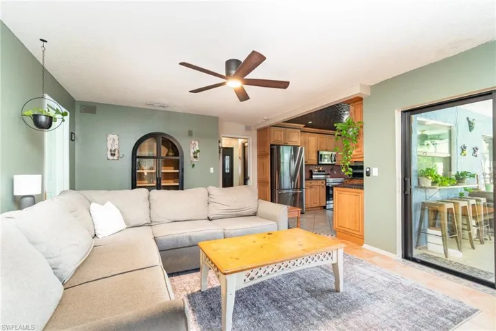 Living area with light tile patterned floors, a ceiling fan, and visible vents